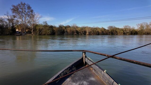 Traditional car ferry crossing the majestic Ebro River in Miravet. Is the last river ferry that allows crossing the Ebro River, consisting of two llaguts connected by a platform that can accommodate