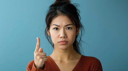 Angry Asian Woman Making A Disapproving Gesture With Her Finger. Conveying a Sense of Disagreement or Refusal - obrazy, fototapety, plakaty