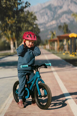 Child girl riding a bike on cycle track outdoor 4 years old kid with helmet training cycling sports activity summer vacations