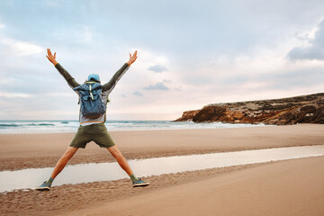 Man with backpack jumping on the beach tourist traveling in Greece healthy lifestyle happy emotions success concept adventure active summer vacations outdoor