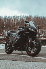 Fototapeta na wymiar Black colored sports motorcycle parked along a deserted mountain road during a winter day