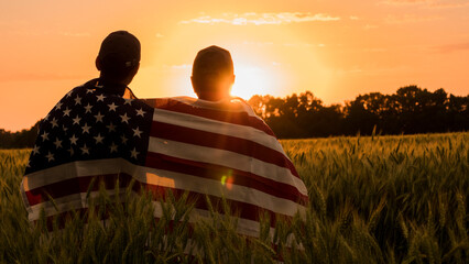 Two men with a usa flag on their shoulders look at the sunset