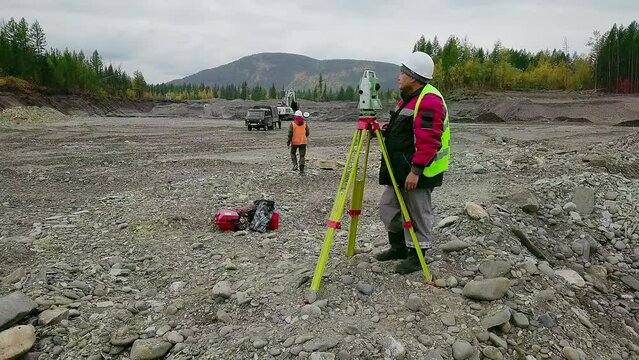 Mine surveyors are using the modern equipment to measure the gold quarry. Mine surveyors are analyzing the location using equipment at the gold quarry. Surveyors examine the gold mine using equipment