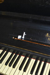 2 3D printed eighth notes in plastic PLA, lying on an antique vintage open cover upright piano in...