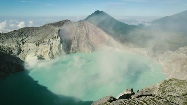 Active volcano Kawah Ijen with sulfur acid lake turquoise color water, smoke emissions from burning sulfur in crater, caldera, East Java, Indonesia. Concept of wild nature landscape, wanderlust