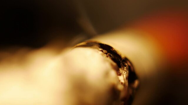 Macro video of a cigarette slowly burning while smoking, out of focus. You can see how the cigarette slowly smolders while smoking.