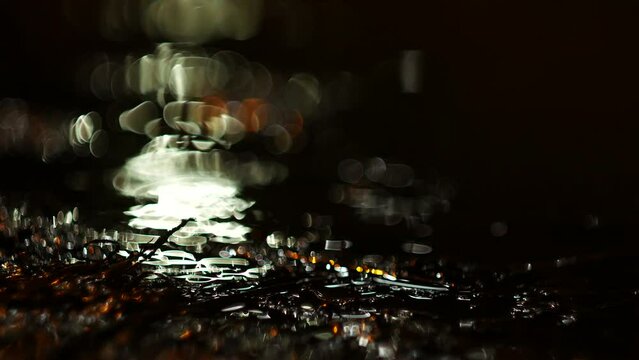 Beautiful background from the reflection of the light of lanterns in the water. The light shimmers in a puddle during the rain.