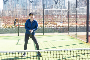 woman playing paddle tennis outdoors.