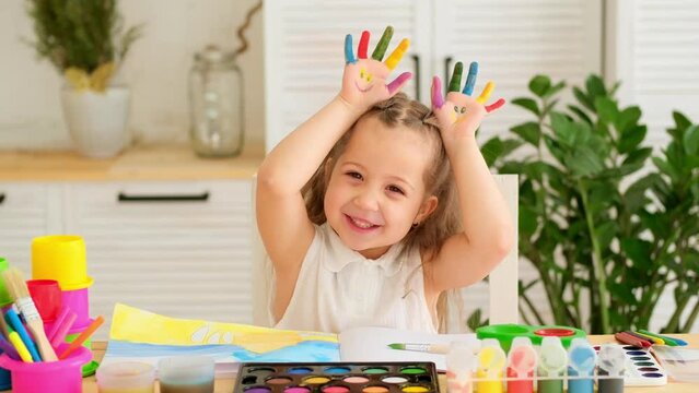 a happy and joyful child dabbles in paints, painting and getting his hands dirty, a little girl learns to draw by playing, a drawing lesson at an art school