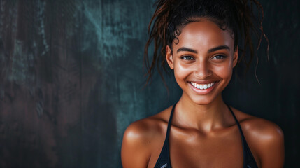 A female fitness model smiling. Dark studio background