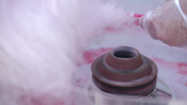 Hands making cotton candy candyfloss with special machine, gimbal stabiliser movement close up.  Machine and human hand at fair.
