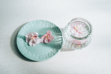 青いお皿の上に乗っている桜と瓶に入った桜