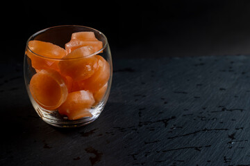 grapefruit juice with ice in a glass on a black background
