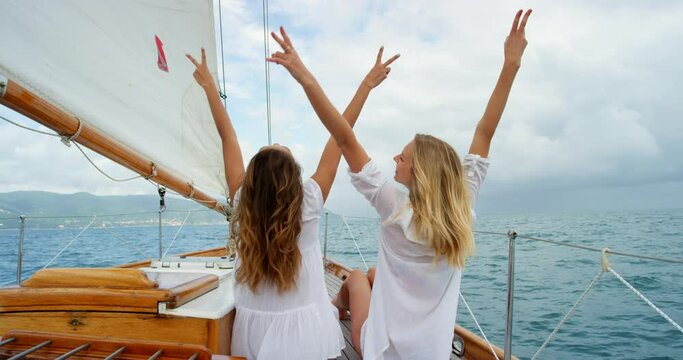 Ocean, friends and excited women on yacht for vacation in Greece, freedom and peace sign from back. Sailing, travel and people on boat deck for island holiday at sea, relax and adventure together.