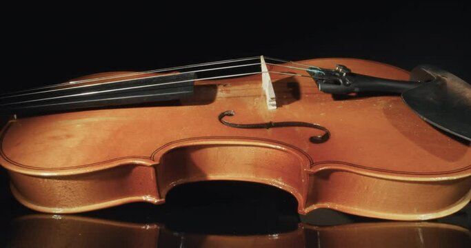 Cinematic shot of antique violin isolated on dark background seen through notes paper curl