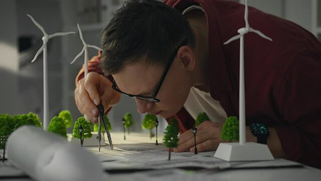 Construction. The project architect is equipped with a tool to effectively place a mini model of the windmill. Architectural engineer designing wind turbine siting plan sustainable urban project plan