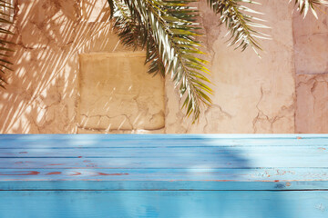 Empty wooden blue table over wall with palm tree shadow background. Summer picnic mock up for design and product display.