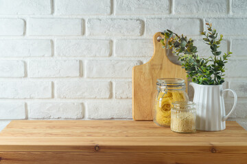 Empty wooden l table with plant, food jars and cutting board over white brick wall  background.  Kitchen mock up for design and product display. - 771498576