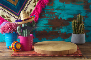 Empty wooden log on  table with cactus decoration over blue wall  background. Mexican party mock up for design and product display