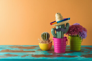 Mexican party concept with cactus and sombrero hat on wooden blue table over colorful background. Cinco de Mayo holiday celebration