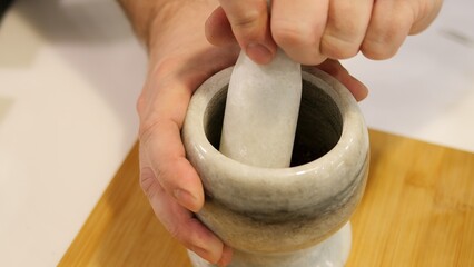 A man carefully grinds spices in mortar creating unique spice blend Spices are thoroughly mixed in mortar giving dish unique aroma and taste Ready made spice from mortar making dish special and tasty