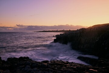 Beautiful sunset over a rocky coast, with waves crashing against the shore. Hermanus, Western Cape.