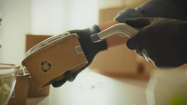 Disposable. A young manager concentrates on scanning a barcode with data in a finished goods warehouse. Warehouse worker uses laser scanner supporting zero waste business concept, cardboard