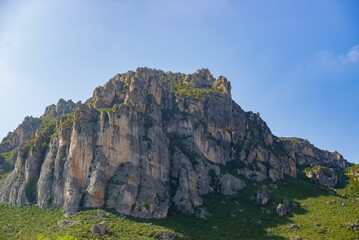 Fototapeta na wymiar Stunning landscape featuring a rocky cliff overlooking lush green grass