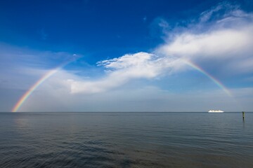 Stunning boat sailing in front of a beautiful rainbow arching over the Chesapeake Bay