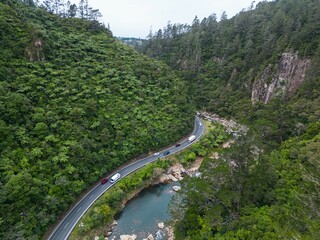 View of a winding road meandering through a lush mountain forest in Karangahake Gorge