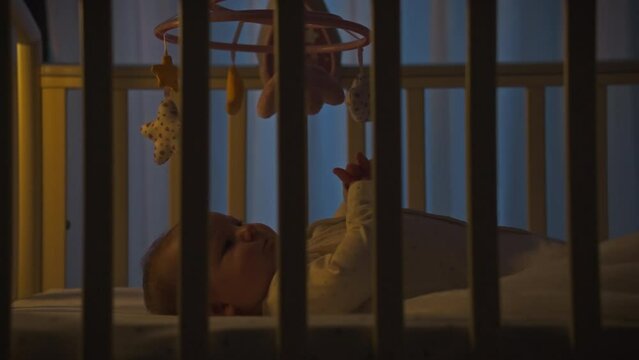 The modern mother pays special attention to the process of putting her child to sleep at night. In the children's room at night, white woman carefully monitors the silence, ensuring the baby's comfort