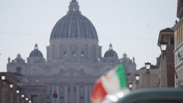 Italian flag fluttering on wind at Via della Conciliazione, Road of Conciliation leading to the Vatican St Peter Square and Basilica. Establishing cinematic shot