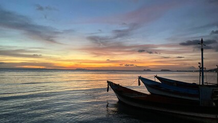 Wooden boats docked at a beach near an island at sunset