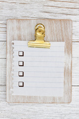 Blank checklist with checkboxes on a wood clipboard with torn paper on wood desk - 771516373