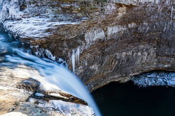 Winter scene of the Desoto Falls cascading over a rocky outcrop in a frosty forest, Alabama