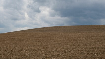 a field with a dirted slope under a cloudy sky