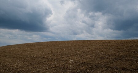a field that has been plowed with dirt under a cloudy sky