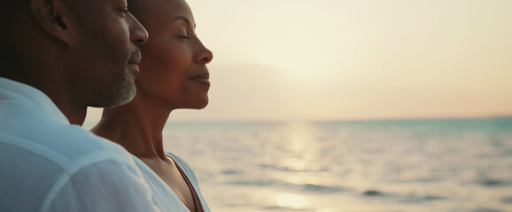 Close up portrait of mature black couple standing together on beach vacation enjoying sunset over the ocean
