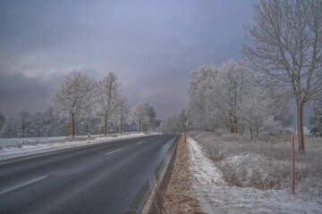 a road on a hill side covered in snow under grey skies