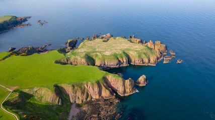 Aerial view of a small lush green island with rocky cliffs at the shore