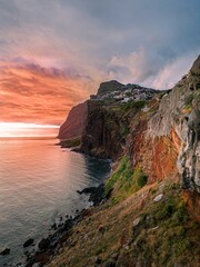 Vertical of a town on top of rocky hills against the sea at sunset