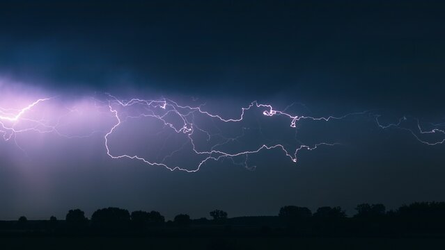 Stunning image of a lightning bolt illuminated in the purple night sky