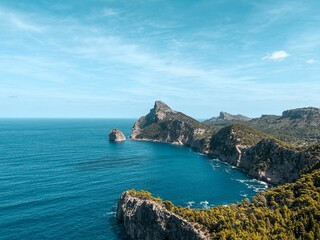 Stunning landscape of the coast featuring rocky cliffs and crystal blue ocean with a bright blue sky