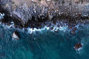 Aerial scenic view of a rocky coastline with splashing blue waves