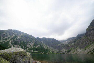 Tranquil natural environment, with a calm lake and distant mountains covered by clouds