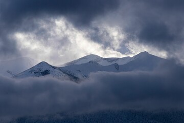 Winter mountain scene with dramatic dark clouds in the sky