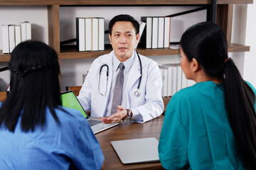 Asian chief physician man is meeting with surgeon doctor women wears blue and green surgical gown....