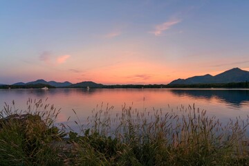 Stunning lake, with a boat sailing on its tranquil surface, set against the sunset sky in Alaska
