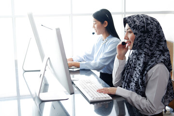 Smiling Asian and Muslim women is call center or secretary operator is wearing a headset and a...