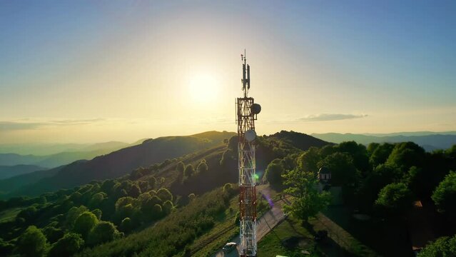 High telecommunication cell tower antenna at mountain high altitude nature on the background of beautiful orange sunset